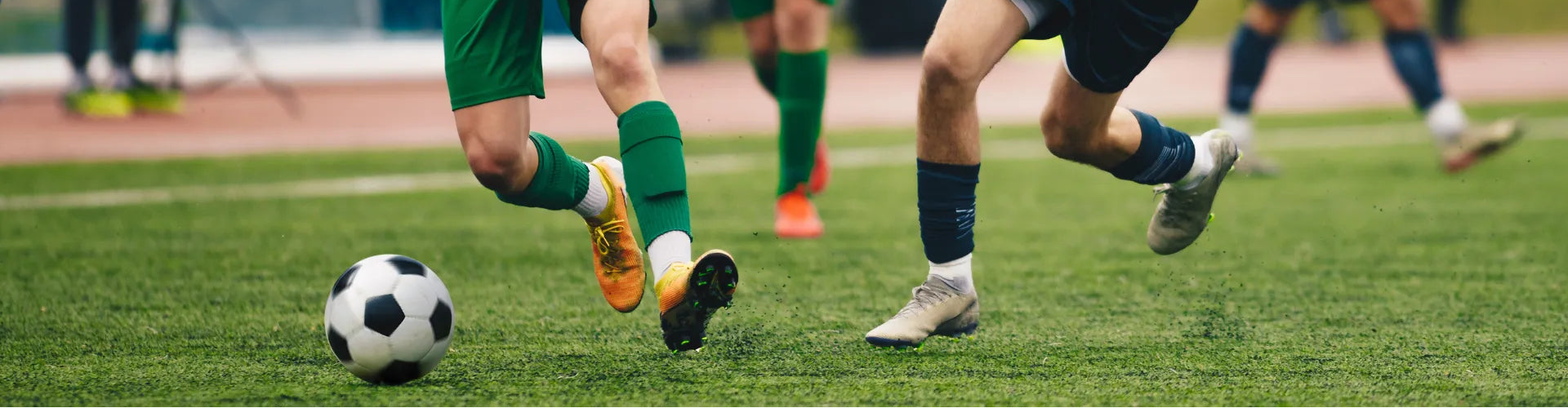 Children playing soccer on a grass field with a focus on one child kicking a soccer ball.